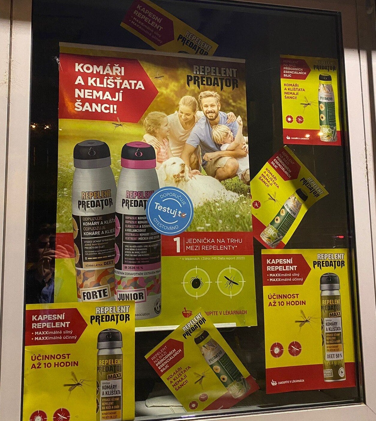 Razítko Testuj.to na plakátu repelentu Predator ve výloze lékárny